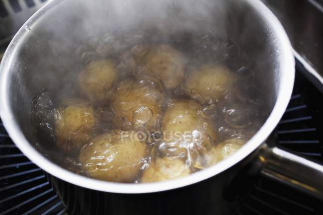La preparación de la ensalada de patatas, las patatas en la cacerola del agua hirviendo - foto de stock