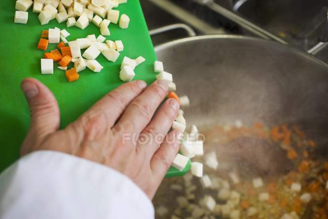 Hand legt Karottenstücke — Stockfoto