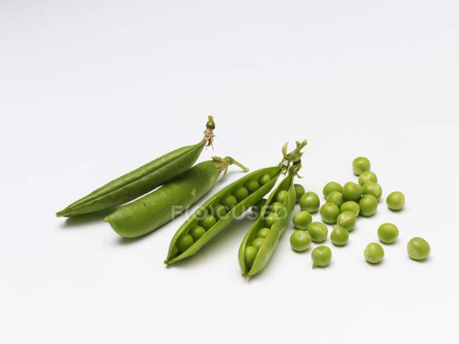 Ripe pea pods on a white surface — Stock Photo