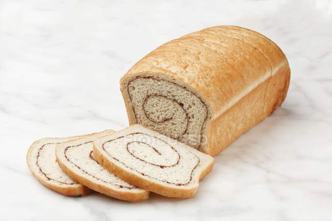 Closeup view of sliced cinnamon loaf on bright marble surface — Stock Photo