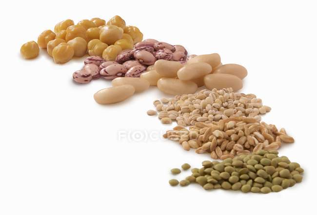 Various legumes and barley  over white surface — Stock Photo
