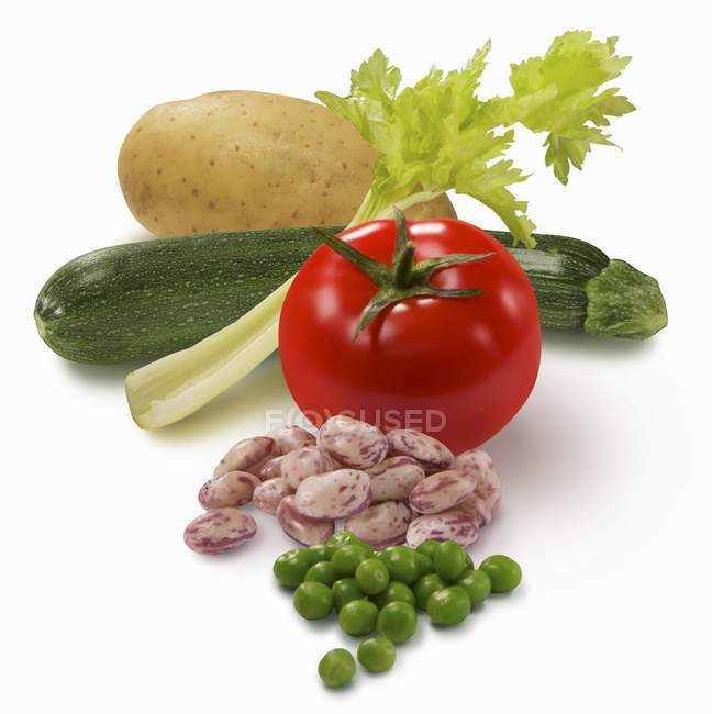 Bodegón vegetal con tomate, pepino, guisantes, frijoles y patata sobre fondo blanco - foto de stock