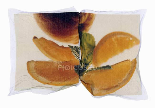 Closeup view of whole and sliced oranges with leaves on a photo print — Stock Photo