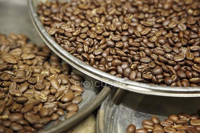 Granos de café en platos de metal - foto de stock