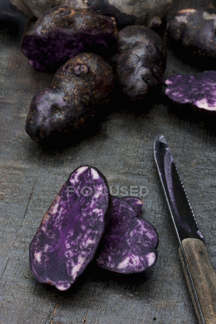 Ganze und in Scheiben geschnittene Vitelotte-Kartoffeln — Stockfoto