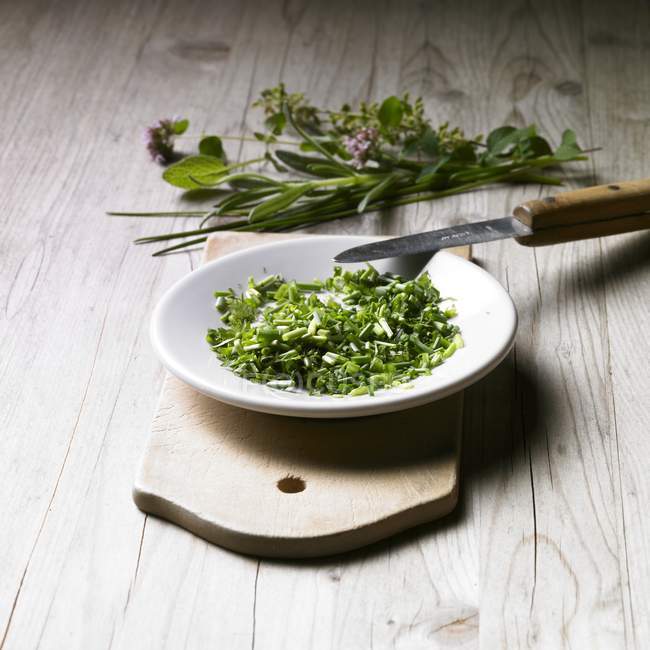 Vista sopraelevata di erbe fresche tritate in ciotola su tavola di legno — Foto stock