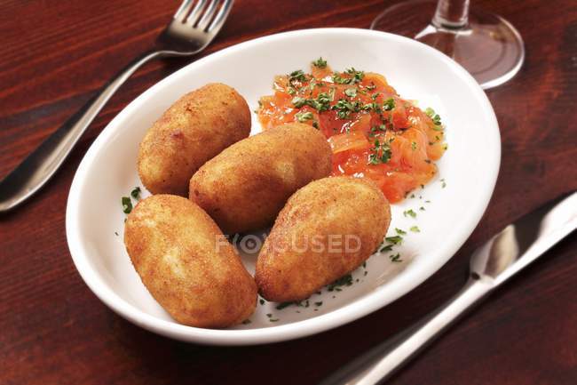 Croquettes de pommes de terre avec sauce tomate sur assiette blanche — Photo de stock