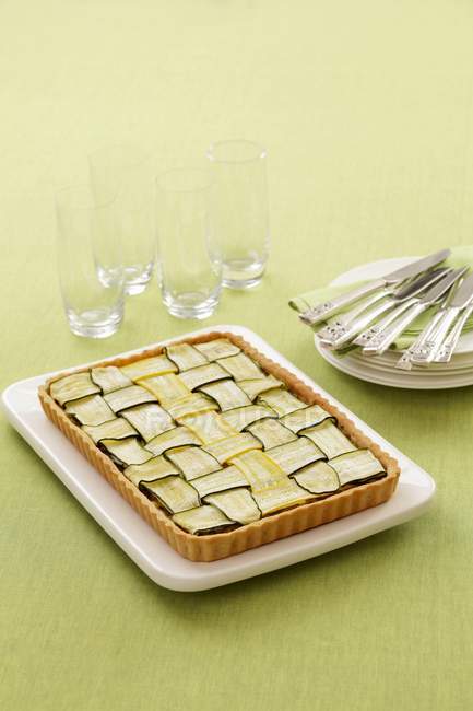 Courgette tart  on white plate over green surface — Stock Photo