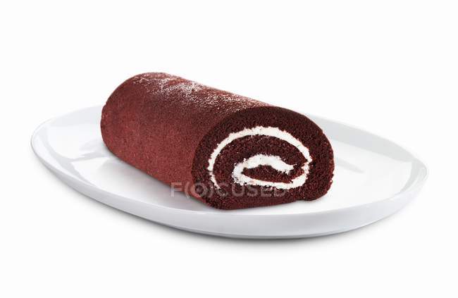 Closeup view of chocolate roll with icing on white plate — Stock Photo