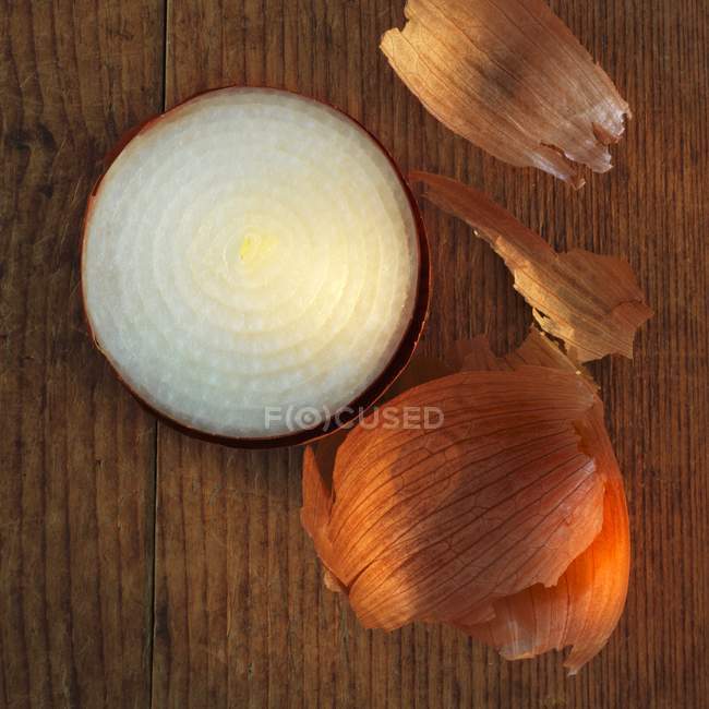 Onion with skin on wooden surface — Stock Photo