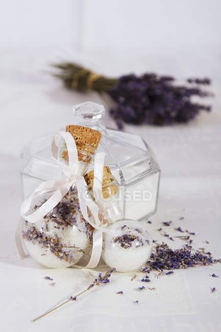 Lavendelzucker in dekorativen Glasgefäßen mit Blüten auf weißer Oberfläche — Stockfoto