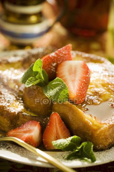 Vista de primer plano de tostadas francesas con jarabe de arce y fresas - foto de stock
