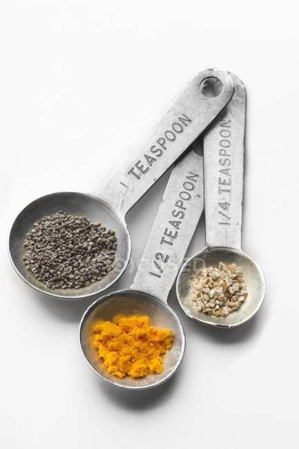 Closeup view of metal measuring spoons set with assorted spices — Stock Photo