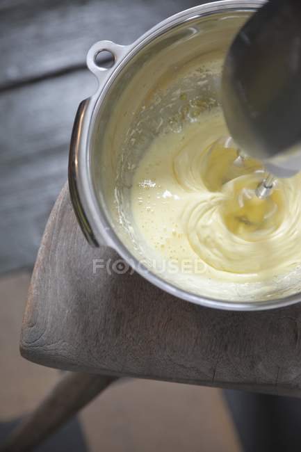 Elevated view of mixing eggs and cream in metal bowl on chair — Stock Photo