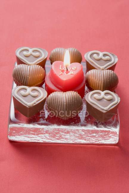 Candle surrounded by chocolates — Stock Photo