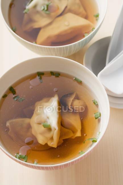 Closeup elevated view of clear broth with Wontons and mushrooms — Stock Photo