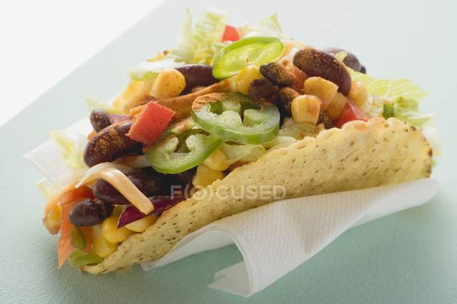 Taco filled with sweetcorn and beans on paper napkin — Stock Photo