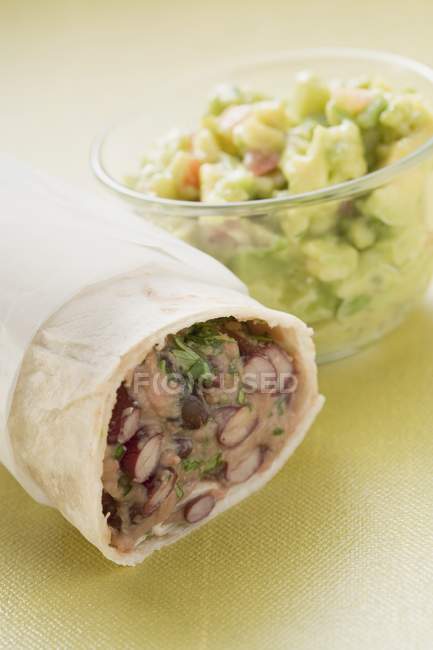 Bean burrito, guacamole in small bowlover green surface — Stock Photo