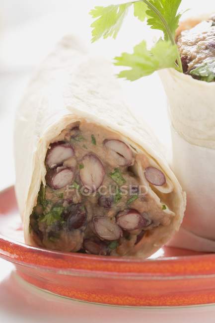 Bean burritos on red glass plate — Stock Photo
