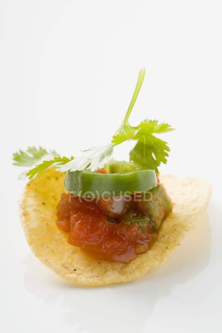 Salsa on tortilla chip on white background — Stock Photo