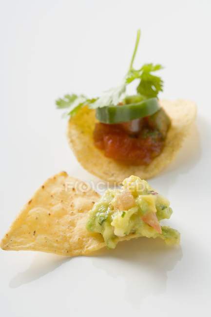 Guacamole on nacho, salsa on tortilla chip on white surface — Stock Photo