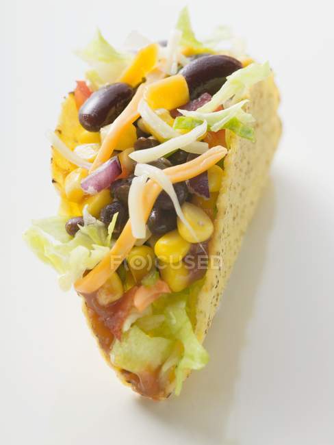 Taco filled with beans and sweetcorn on white surface — Stock Photo