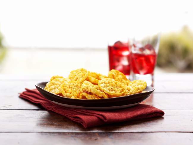 Vue rapprochée des chips de poivre croustillantes sur l'assiette et la serviette pliée — Photo de stock