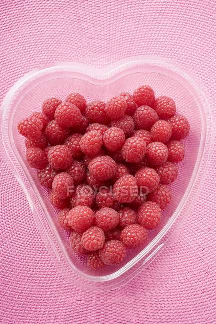 Raspberries in heart-shaped container — Stock Photo