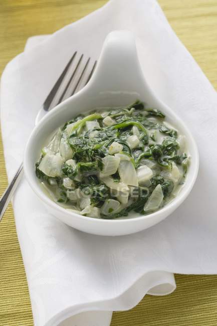 Spinach with onions in small pot over towel with fork — Stock Photo