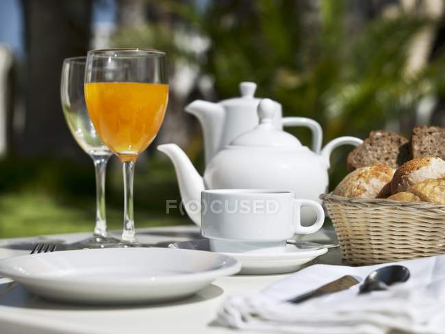 Сніданок на садовому столі з чайниками та чашками на відкритому повітрі — стокове фото