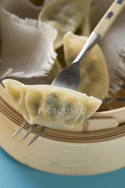 Closeup view of Wontons in bamboo steamer with fork — Stock Photo
