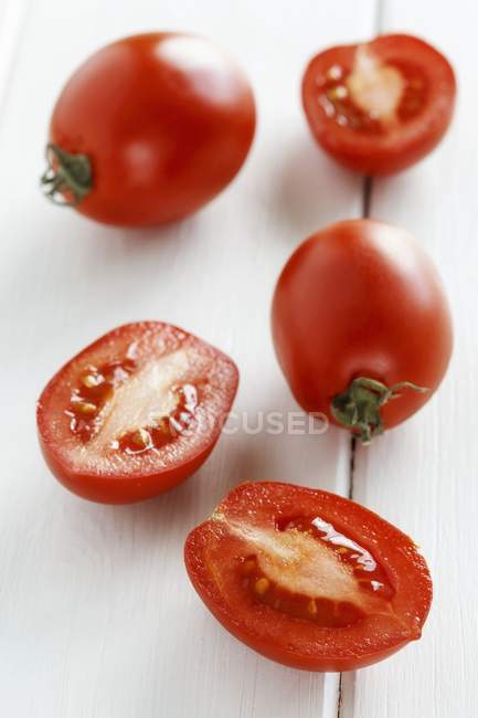 Tomates roma enteros y cortados a la mitad - foto de stock