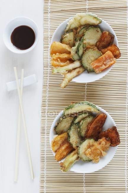 Vegetable tempura with soy sauce over straw mat — Stock Photo