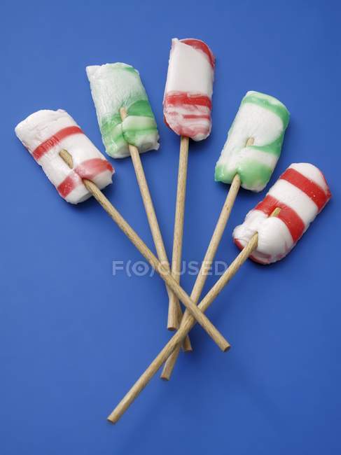 Closeup top view of five striped lollies on blue surface — Stock Photo