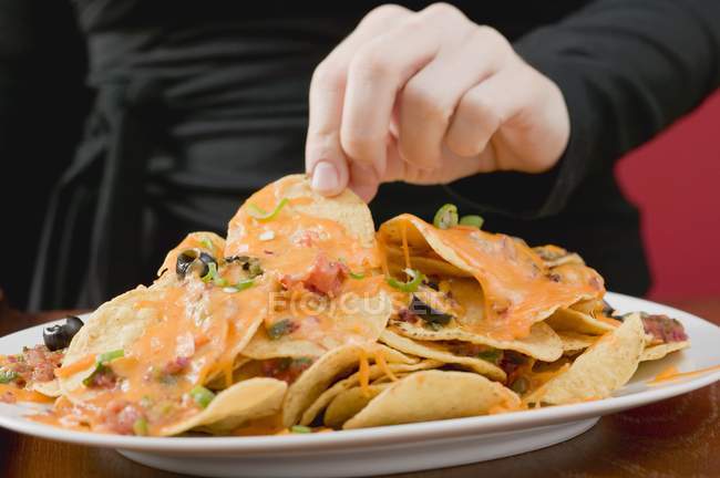 Hand reaching for tortilla chips — Stock Photo