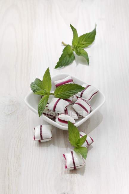 Closeup view of peppermint bonbons and fresh mint leaves — Stock Photo