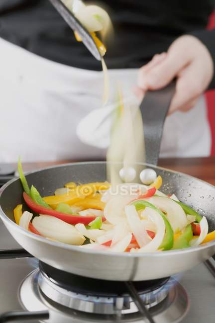 Saltear verduras en sartén en la cocina - foto de stock