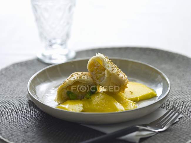 Blätterteigrollen mit Mango auf weißem Teller über Tisch — Stockfoto