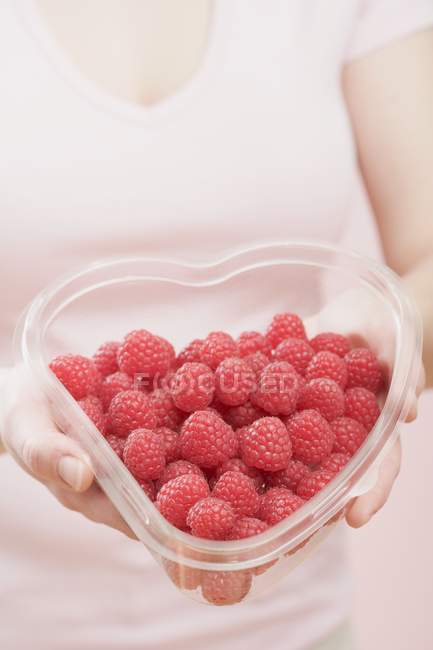 Woman holding container of raspberries — Stock Photo