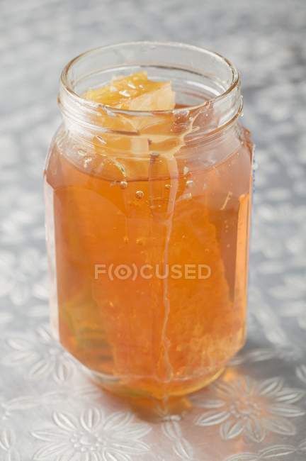 Jar with honeycomb on tablecloth — Stock Photo