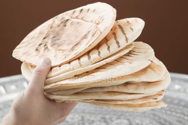 Рука тримає на грилі плоскі хліби — стокове фото