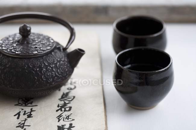 Tetera y tazones de té negro - foto de stock