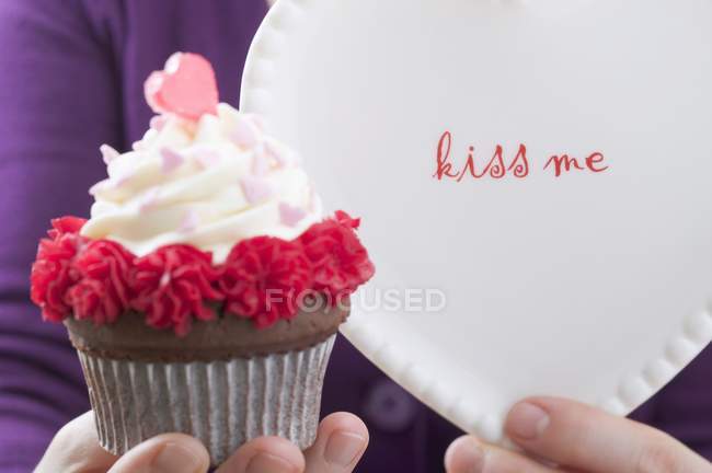Mujer mano celebración de San Valentín cupcake - foto de stock