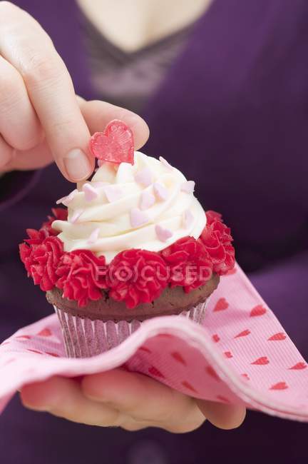 Mujer mano celebración de San Valentín cupcake - foto de stock