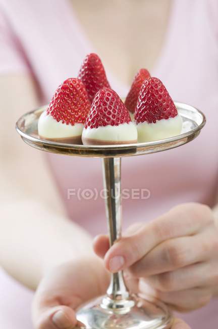 Closeup view of woman holding chocolate-dipped strawberries on silver stand — Stock Photo