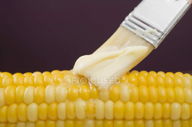 Brushing corn on the cob — Stock Photo