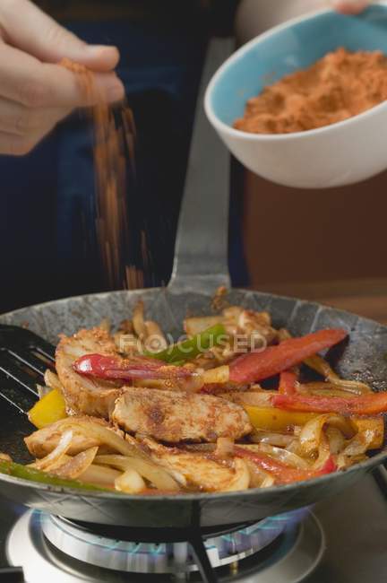 Ajouter la poudre de piment au poulet avec les oignons et les poivrons — Photo de stock