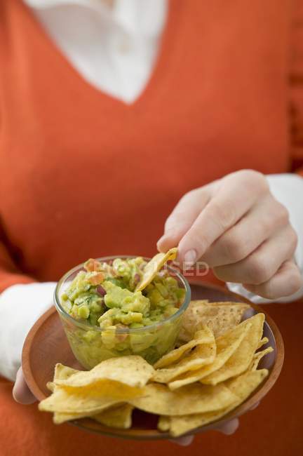Closeup view of woman dipping Nacho in Guacamole in bowl — Stock Photo