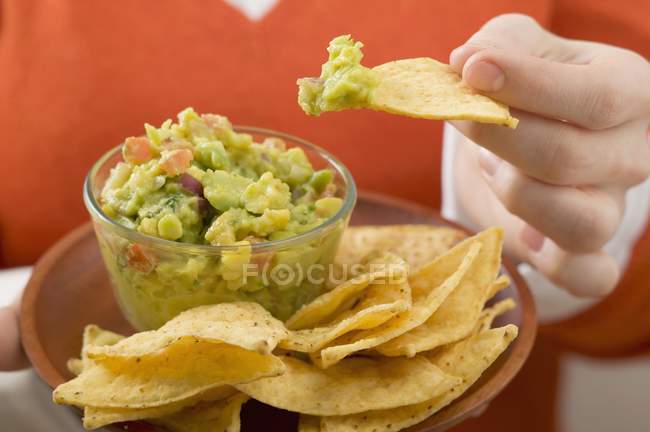 Mulher mergulhando nacho em guacamole — Fotografia de Stock