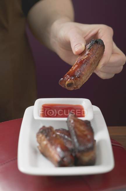 Woman holding glazed pork rib — Stock Photo